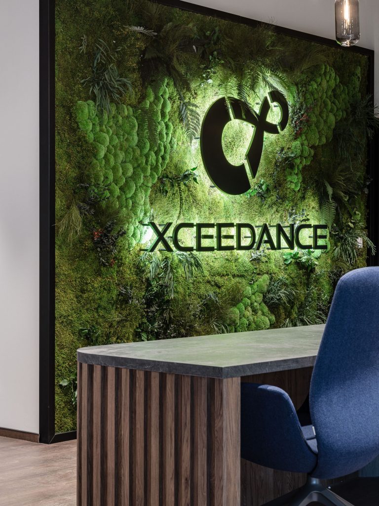 Biuro Xceedance w Krakowie – zielona ściana z logo, projekt The Design Group